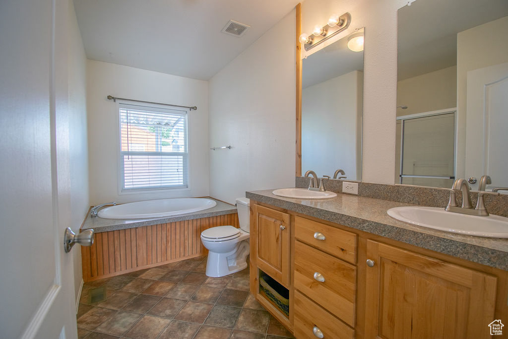 Full bathroom featuring a garden tub, double vanity, a stall shower, and stone finish flooring