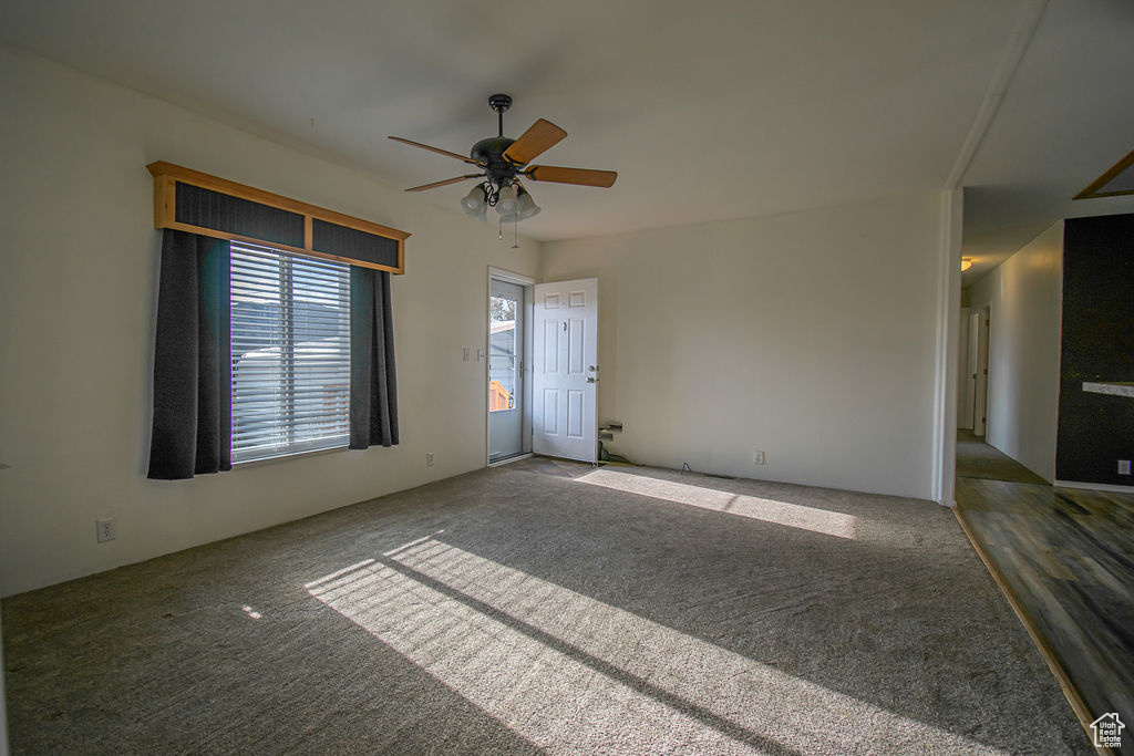 Empty room featuring ceiling fan and carpet floors