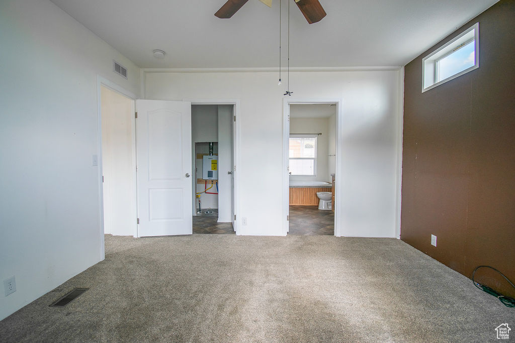 Unfurnished bedroom with carpet, ensuite bathroom, and ceiling fan