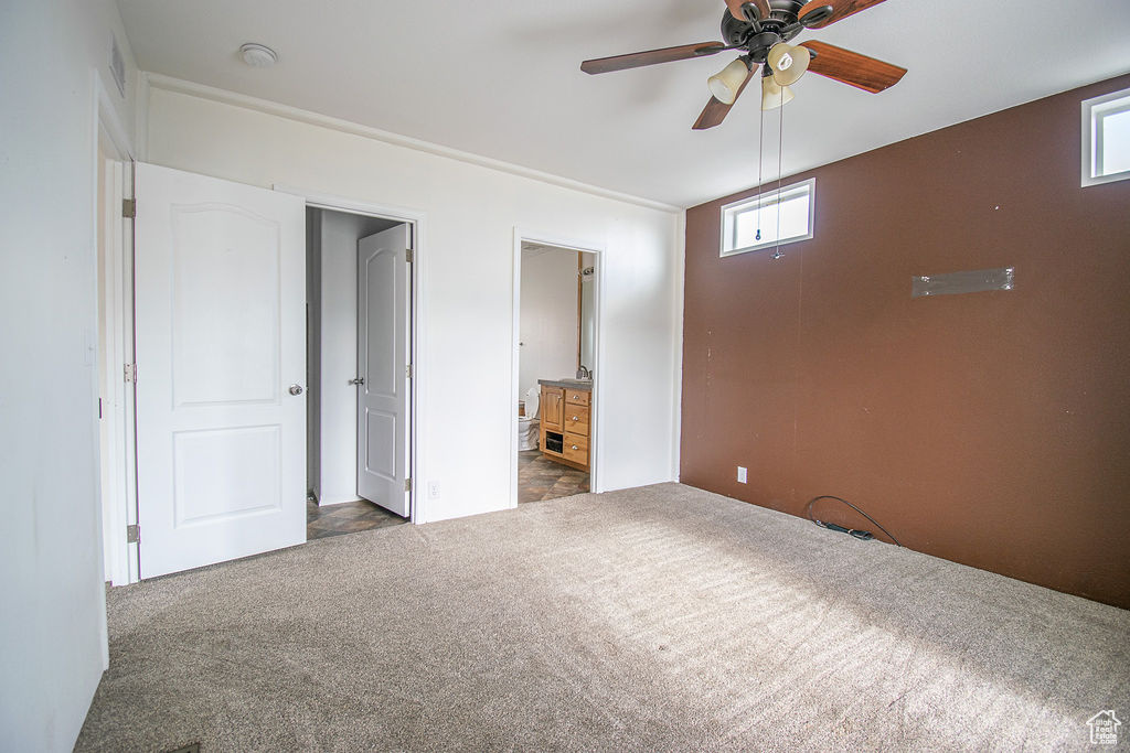 Unfurnished bedroom with dark colored carpet and ensuite bath