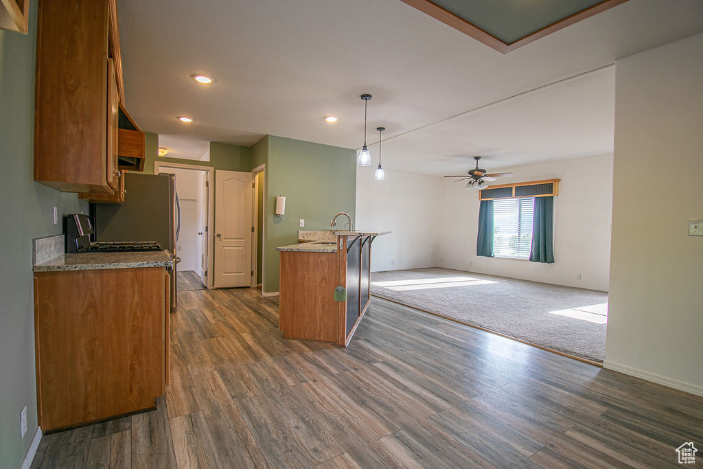 Kitchen with brown cabinetry, dark wood-type flooring, recessed lighting, a ceiling fan, and pendant lighting