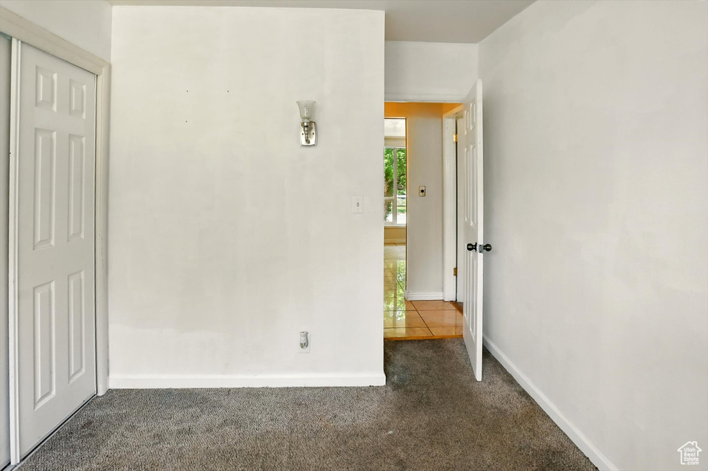 Unfurnished bedroom with dark colored carpet and baseboards