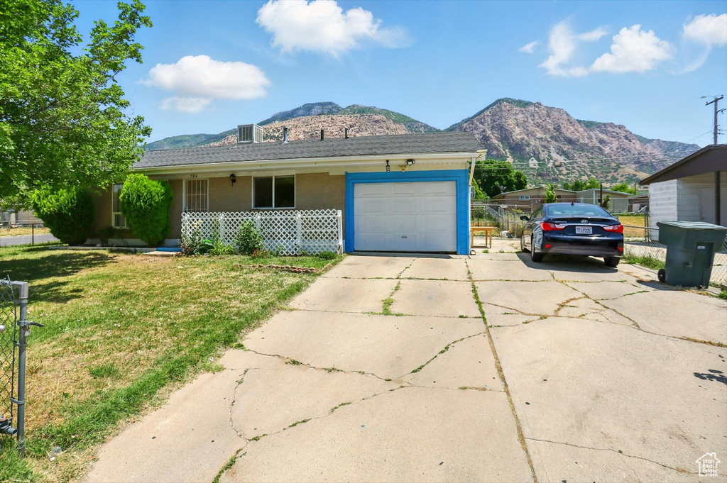 Ranch-style home with a mountain view, driveway, a garage, covered porch, and a front lawn