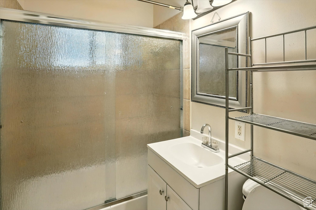 Full bathroom with vanity and enclosed tub / shower combo