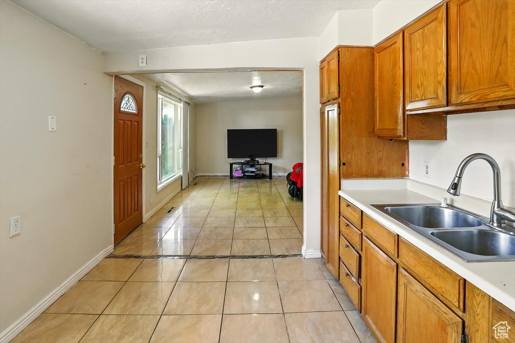 Kitchen featuring a textured ceiling, brown cabinets, light countertops, light tile patterned floors, and open floor plan