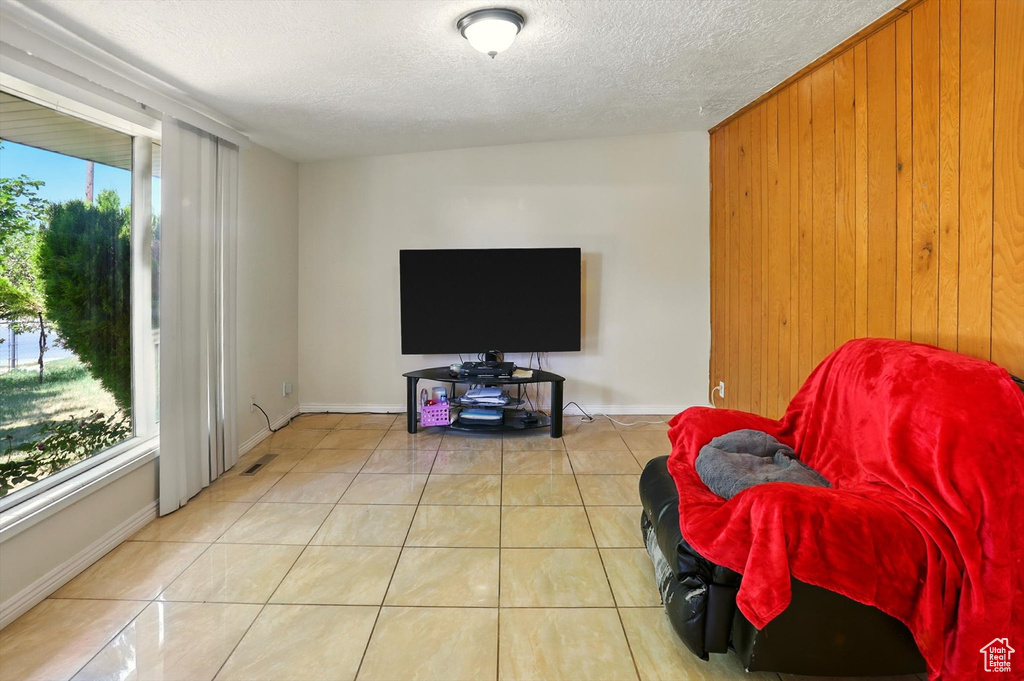 Living room featuring wooden walls, a textured ceiling, and tile patterned floors