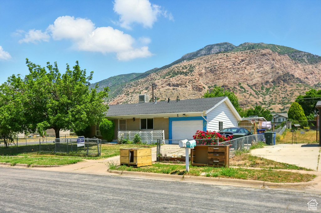 Ranch-style home with a fenced front yard, a mountain view, a garage, and concrete driveway