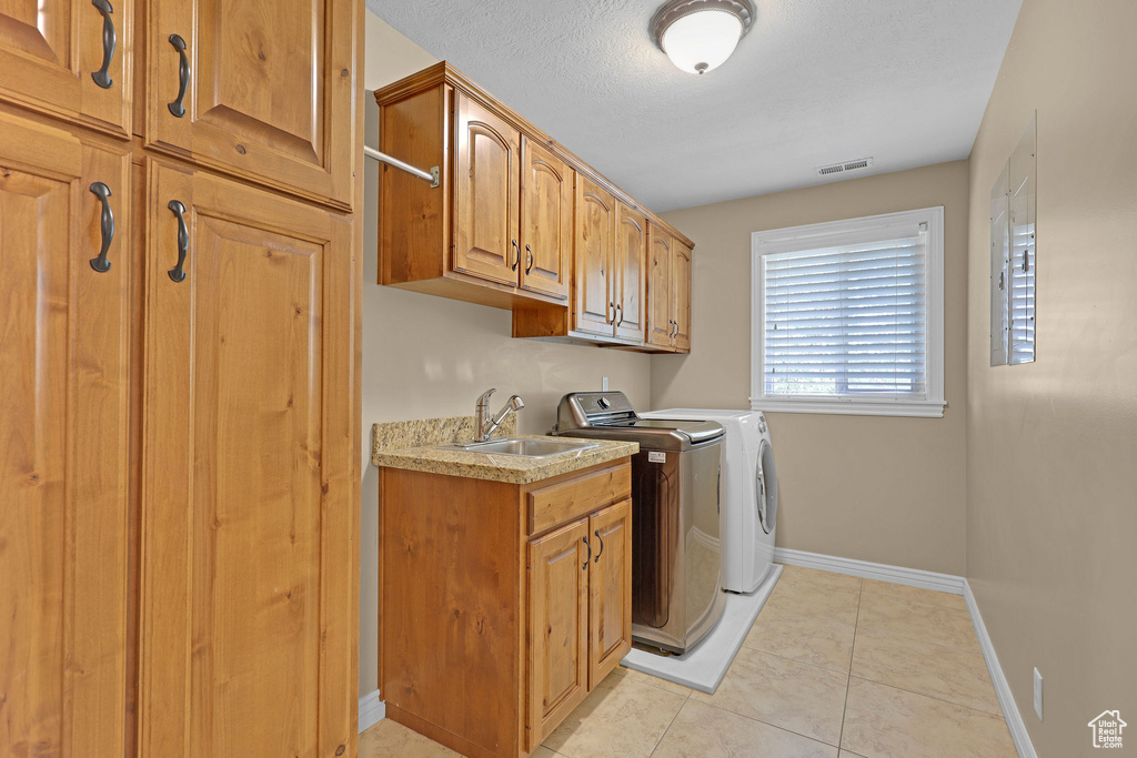 Laundry area with washing machine and clothes dryer, cabinet space, and light tile patterned floors