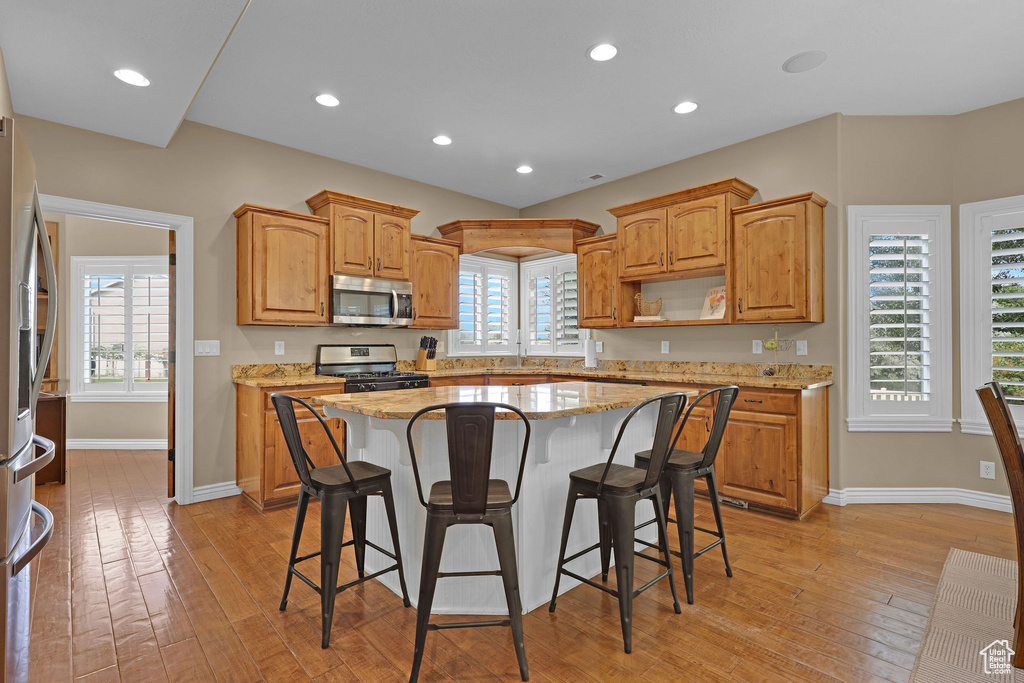 Kitchen featuring stainless steel appliances, light wood-style floors, a breakfast bar, and recessed lighting