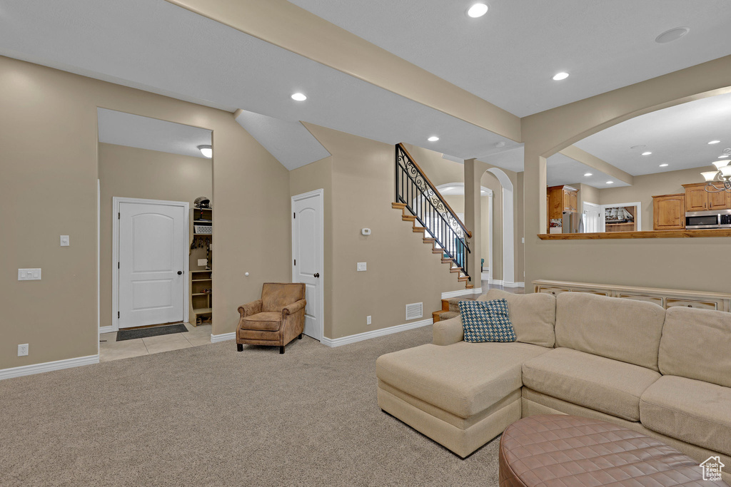 Living room with arched walkways, light carpet, recessed lighting, and stairway