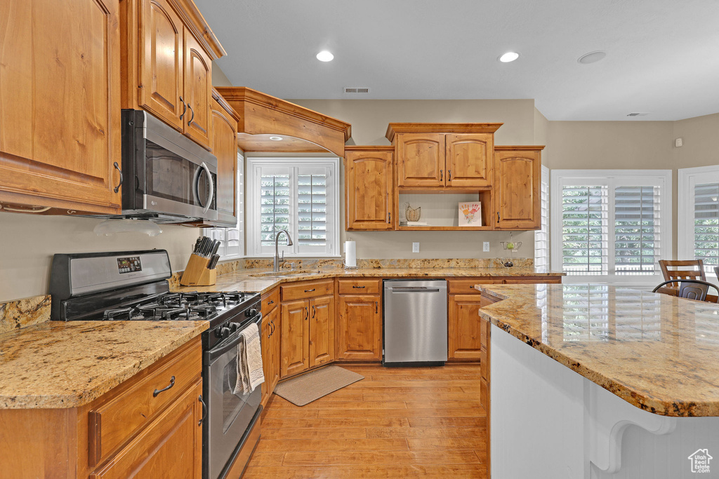 Kitchen featuring stainless steel appliances, healthy amount of natural light, light wood-style flooring, light stone counters, and recessed lighting