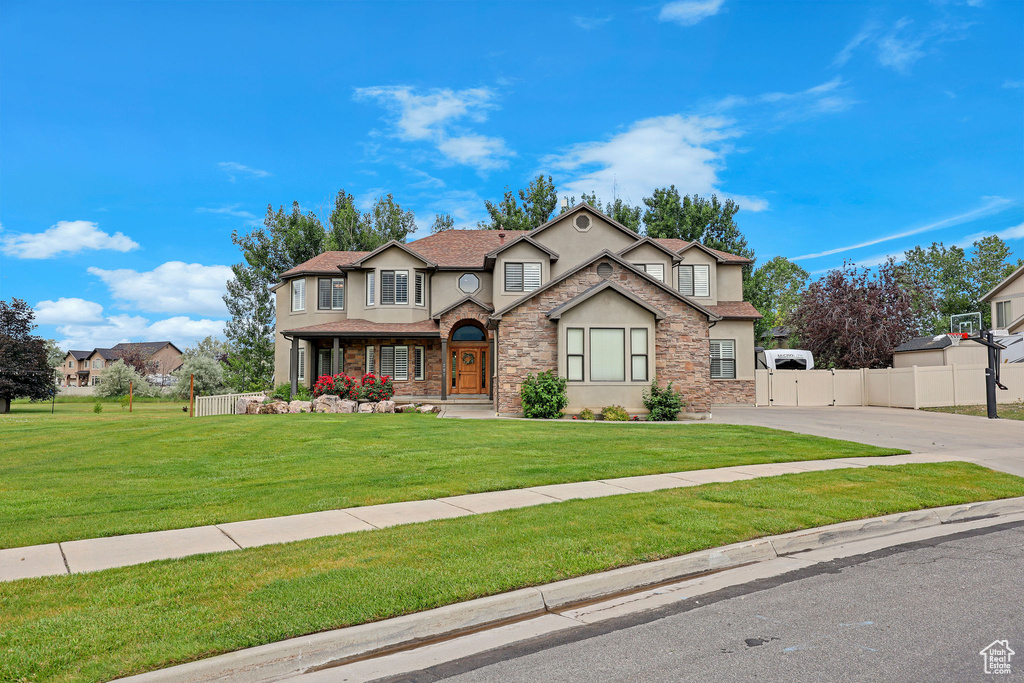 View of front of home featuring stucco siding, concrete driveway, a gate, and stone siding