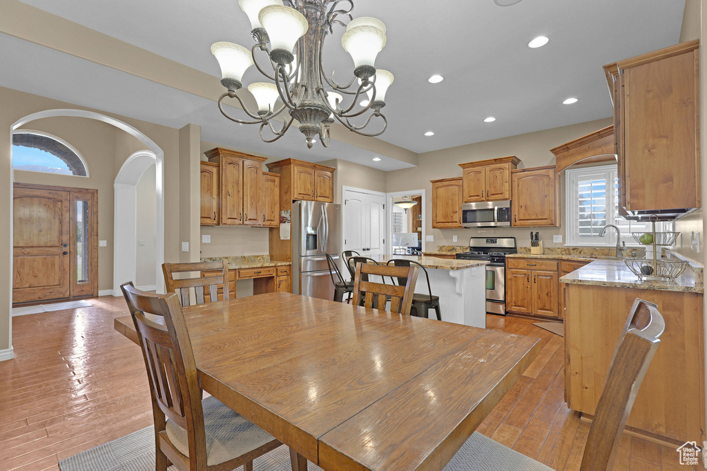 Dining room with arched walkways, a chandelier, recessed lighting, and light wood finished floors