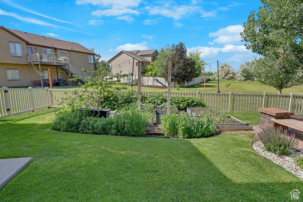 Fenced backyard featuring a vegetable garden and a residential view