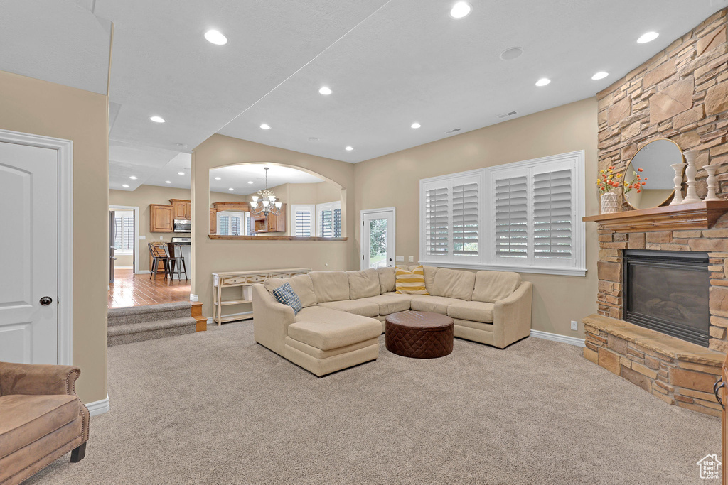Living room with carpet flooring, recessed lighting, a chandelier, and a fireplace
