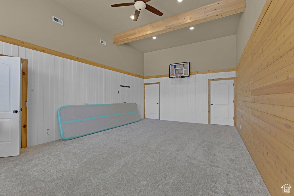 Carpeted empty room featuring a ceiling fan, wood walls, wainscoting, beamed ceiling, and recessed lighting