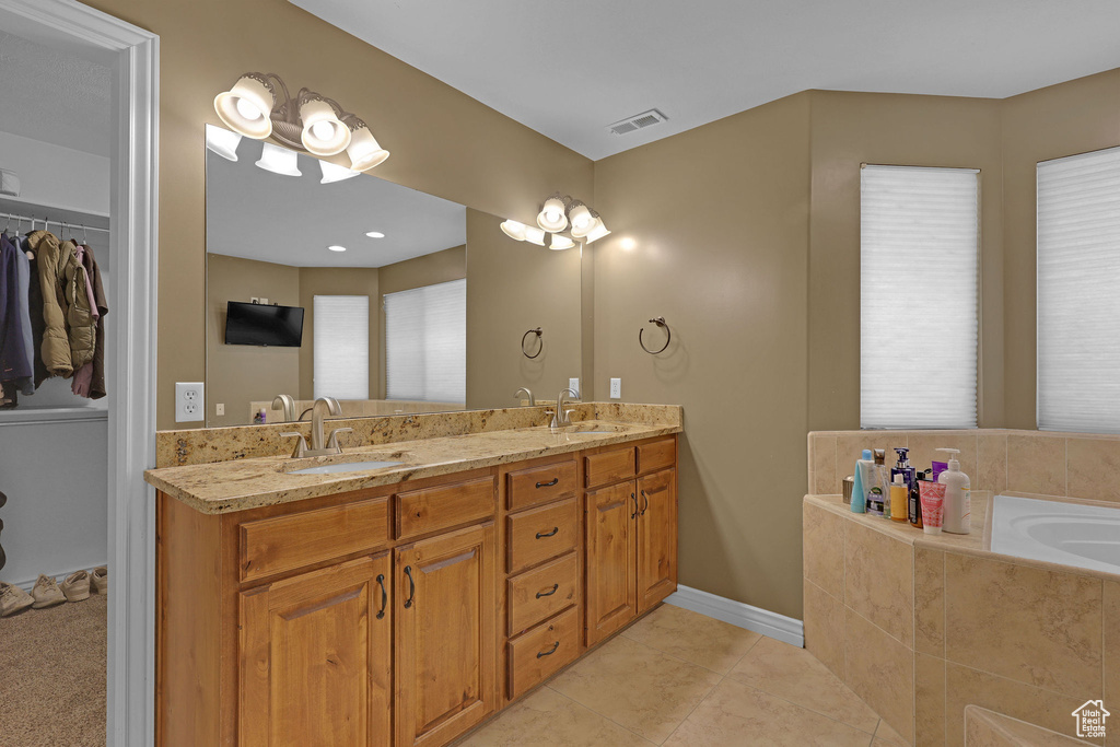 Full bathroom with double vanity, a bath, tile patterned flooring, and a walk in closet