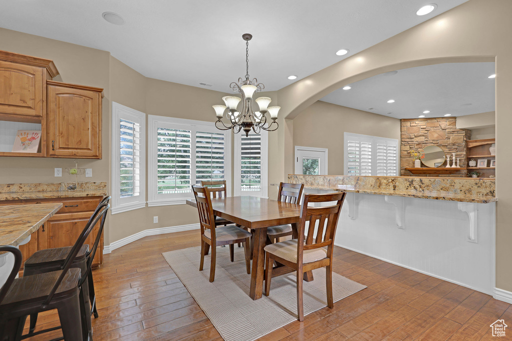 Dining space featuring light wood finished floors, a chandelier, arched walkways, plenty of natural light, and recessed lighting