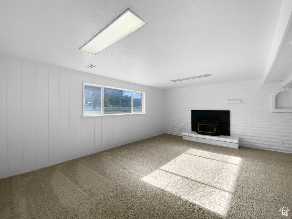 Unfurnished living room with a fireplace with raised hearth and carpet floors