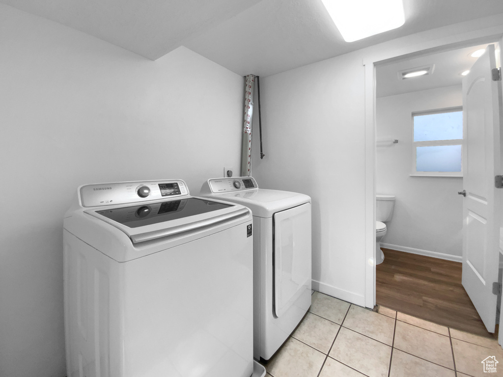 Washroom with washing machine and dryer and light tile patterned floors