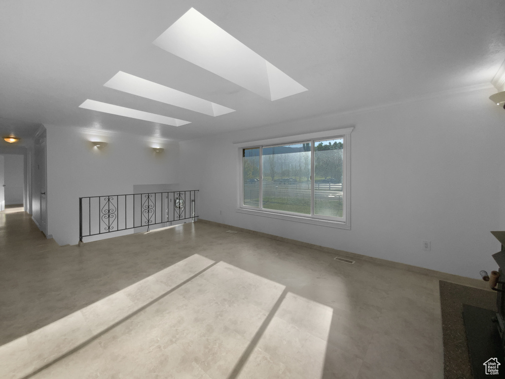 Empty room with finished concrete floors, a skylight, and ornamental molding