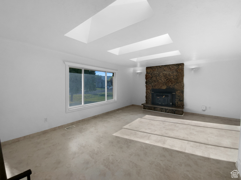 Unfurnished living room with a skylight and a stone fireplace