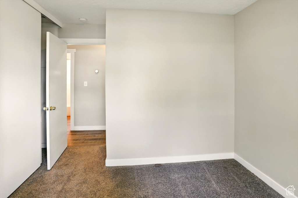 Carpeted empty room featuring baseboards and a smoke detector