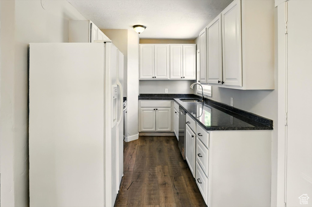 Kitchen featuring white fridge with ice dispenser, white cabinetry, and dark wood-style flooring