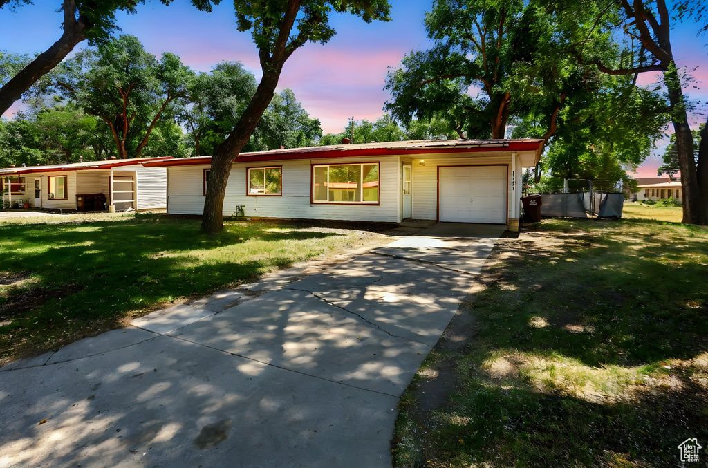 Single story home featuring a garage, concrete driveway, and a yard