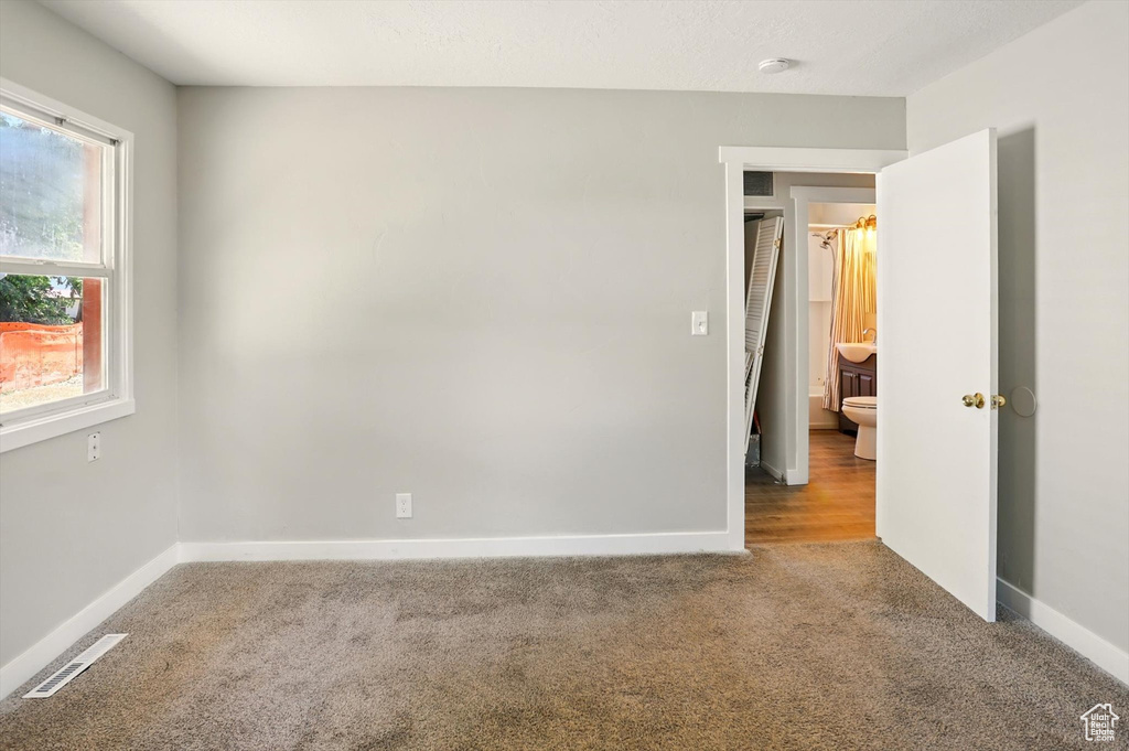 Carpeted empty room featuring baseboards and a smoke detector