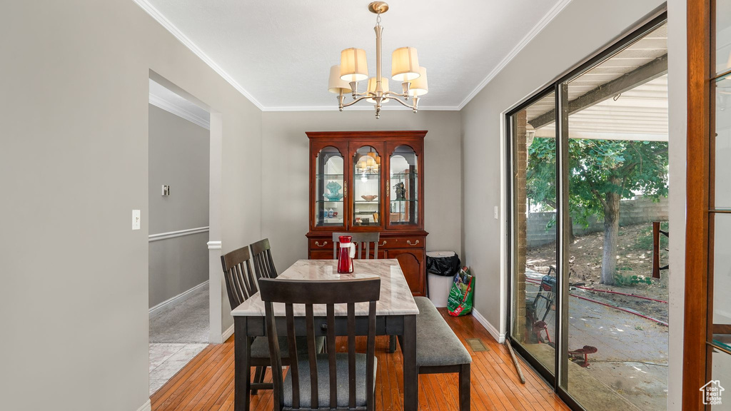 Dining area featuring light wood-style flooring, a chandelier, and ornamental molding