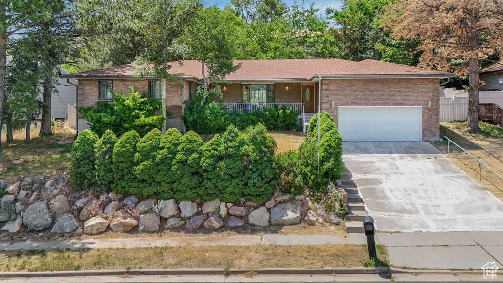 Single story home with brick siding, a garage, covered porch, and driveway