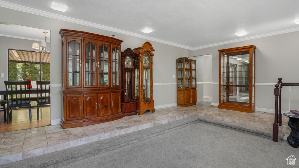 Foyer entrance with ornamental molding, a chandelier, and light tile patterned floors