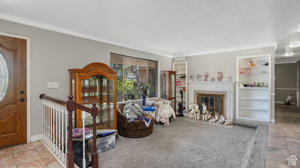 Living area featuring built in features, ornamental molding, and a fireplace with flush hearth