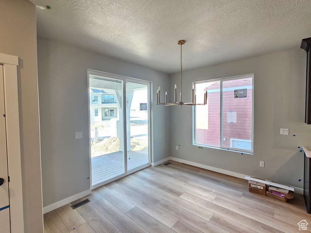 Unfurnished dining area with light wood-style floors and a textured ceiling