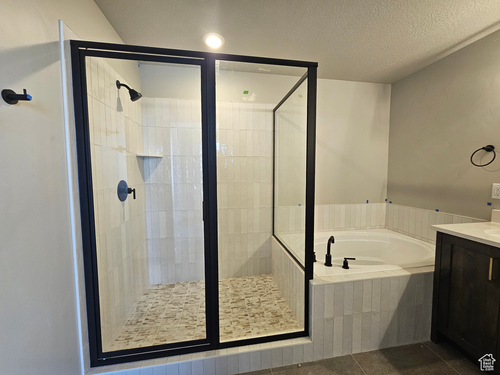 Bathroom with vanity, a garden tub, a shower stall, tile patterned floors, and a textured ceiling