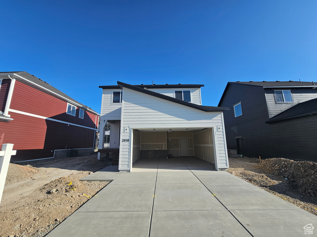 View of front of property featuring concrete driveway and an attached garage