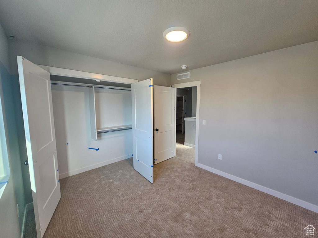 Unfurnished bedroom featuring light colored carpet and a closet