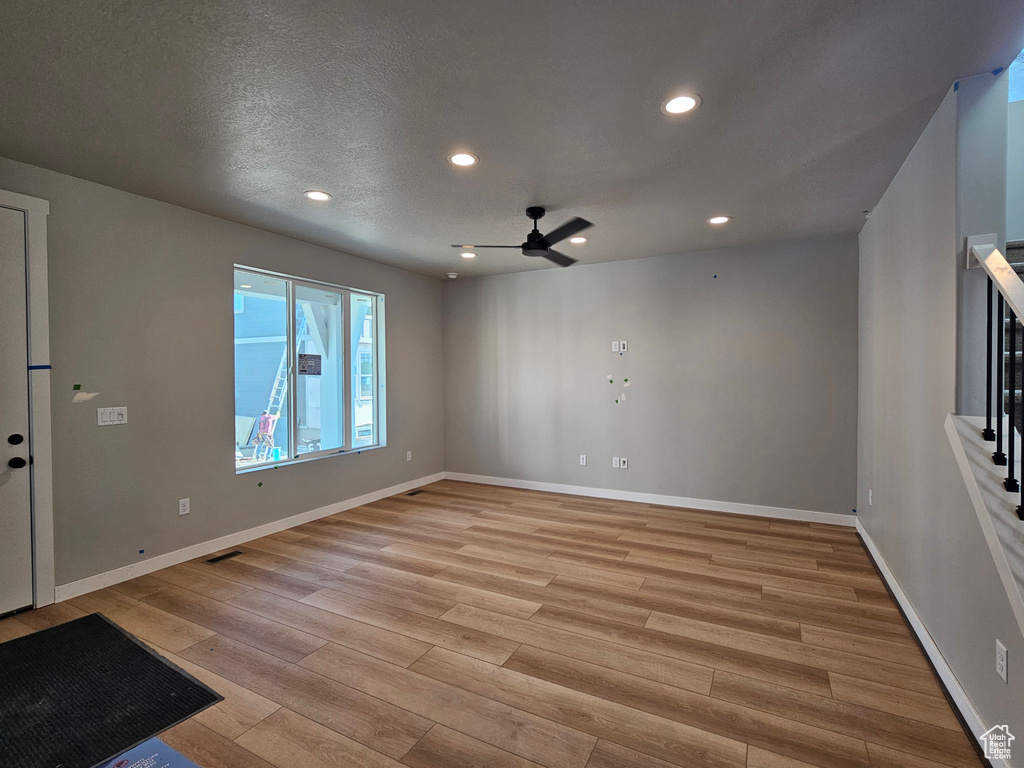 Unfurnished room featuring light wood finished floors, ceiling fan, recessed lighting, and stairs