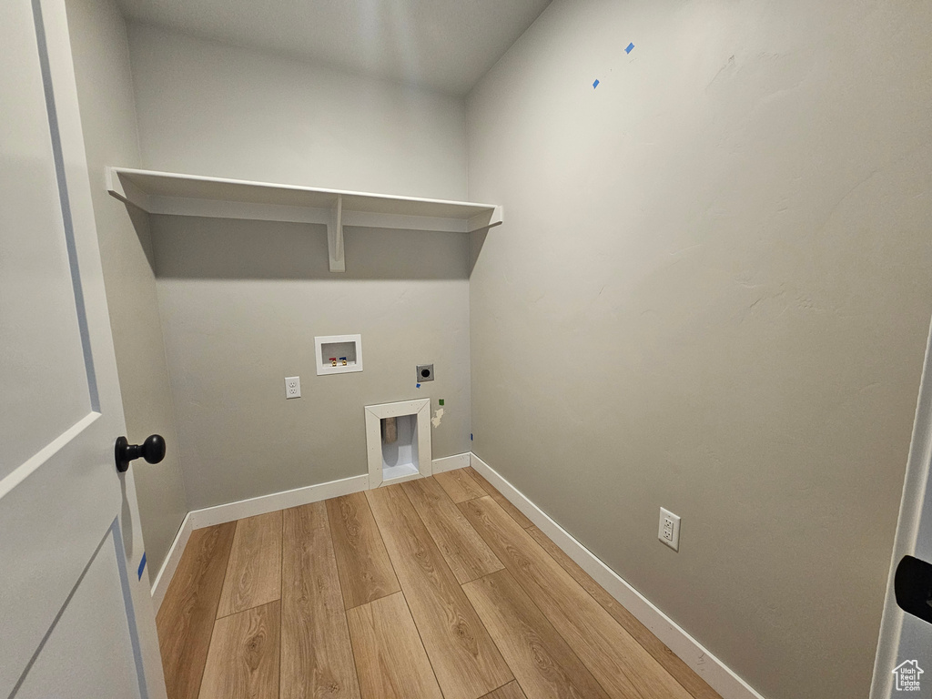 Laundry room with hookup for an electric dryer, light wood-style floors, and hookup for a washing machine