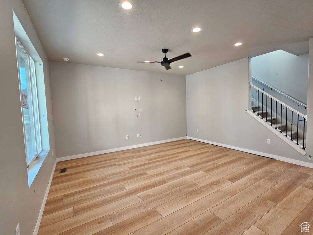 Empty room with light wood-type flooring, recessed lighting, ceiling fan, and stairs