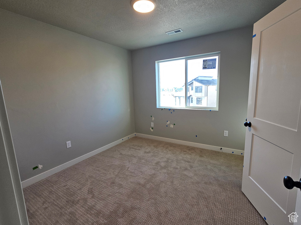 Spare room with a textured ceiling and light carpet
