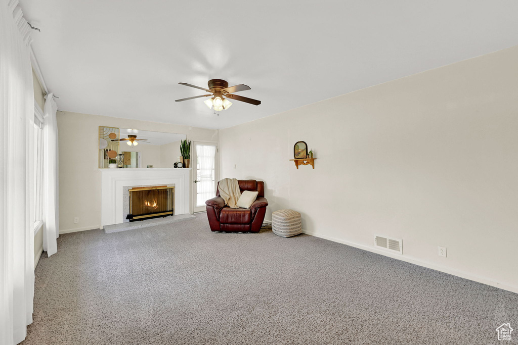 Living area featuring carpet flooring, ceiling fan, and a glass covered fireplace