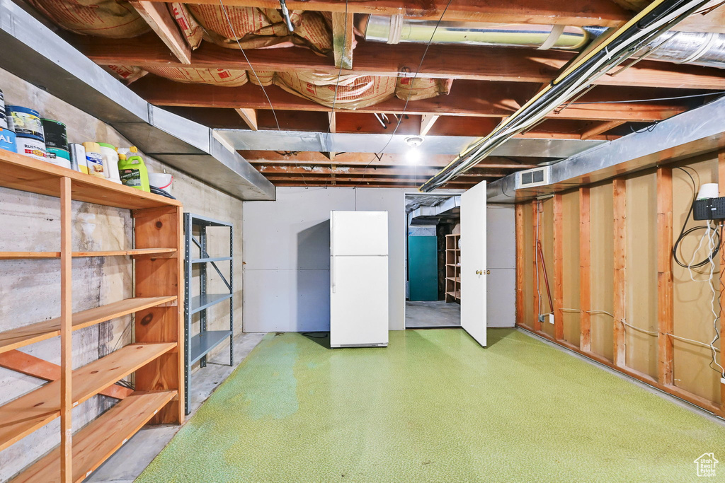 Unfinished basement with freestanding refrigerator