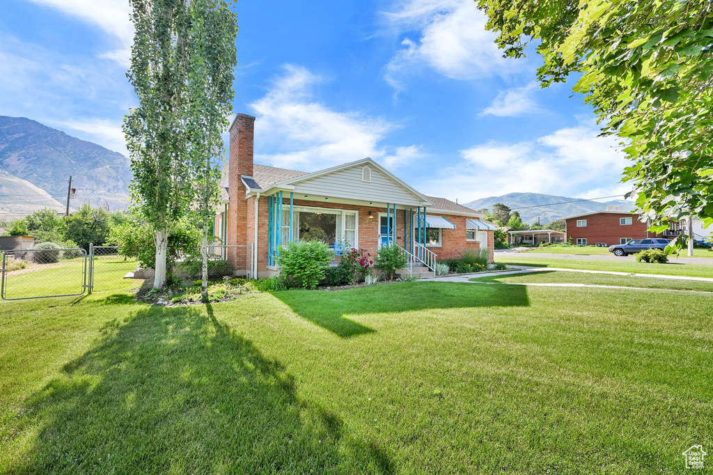 Bungalow-style home with a mountain view, a chimney, brick siding, and a gate