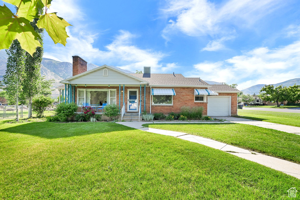 View of front of property featuring a mountain view, brick siding, covered porch, an attached garage, and concrete driveway