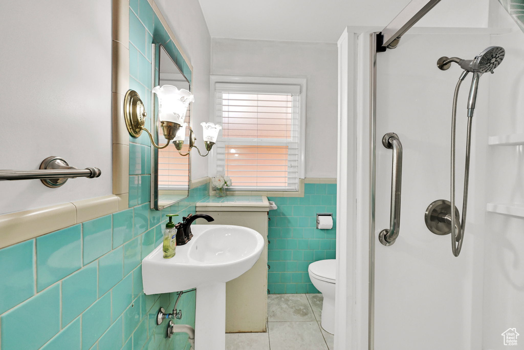 Bathroom featuring tile patterned floors, tile walls, a shower stall, and a wainscoted wall