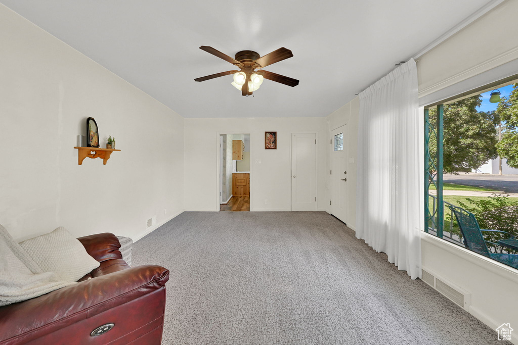 Carpeted living room with ceiling fan