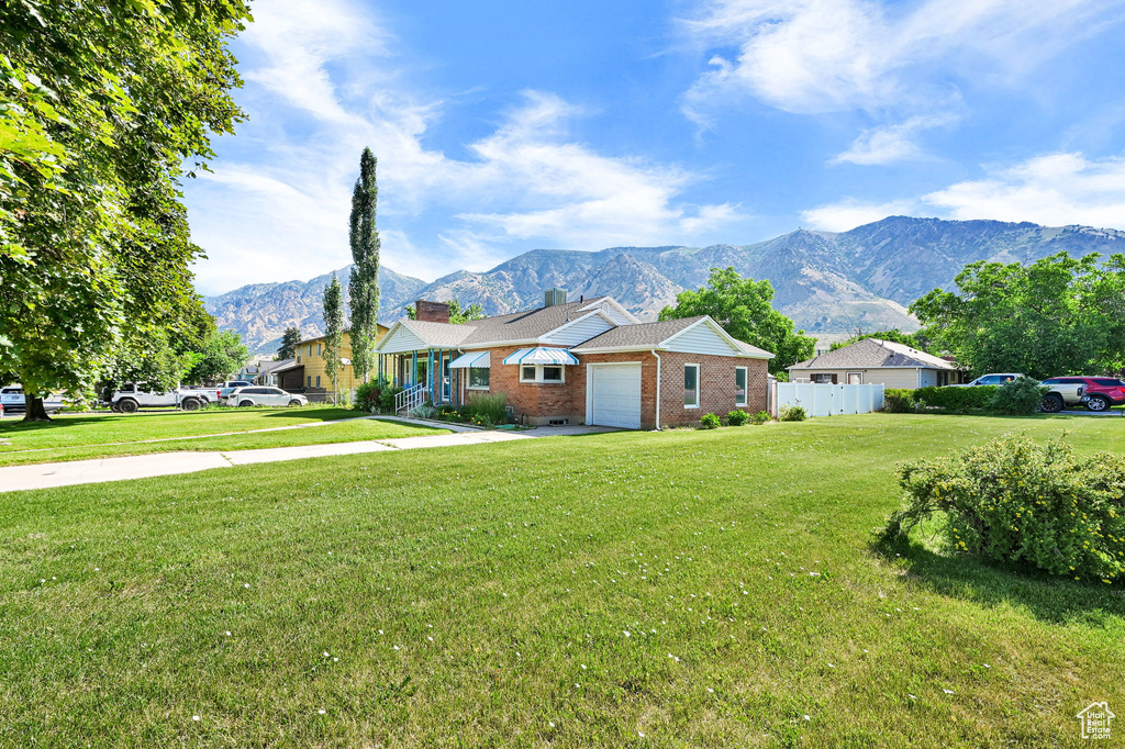 View of front of house with a garage, brick siding, a mountain view, a chimney, and driveway