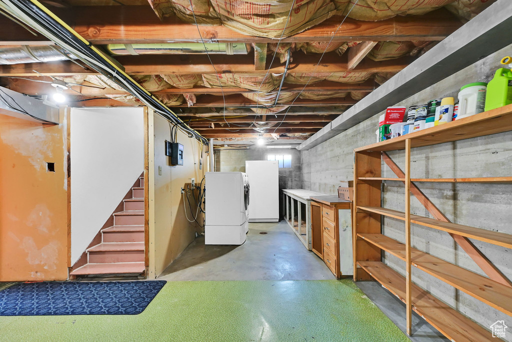 Basement featuring freestanding refrigerator, fridge, stairs, and independent washer and dryer